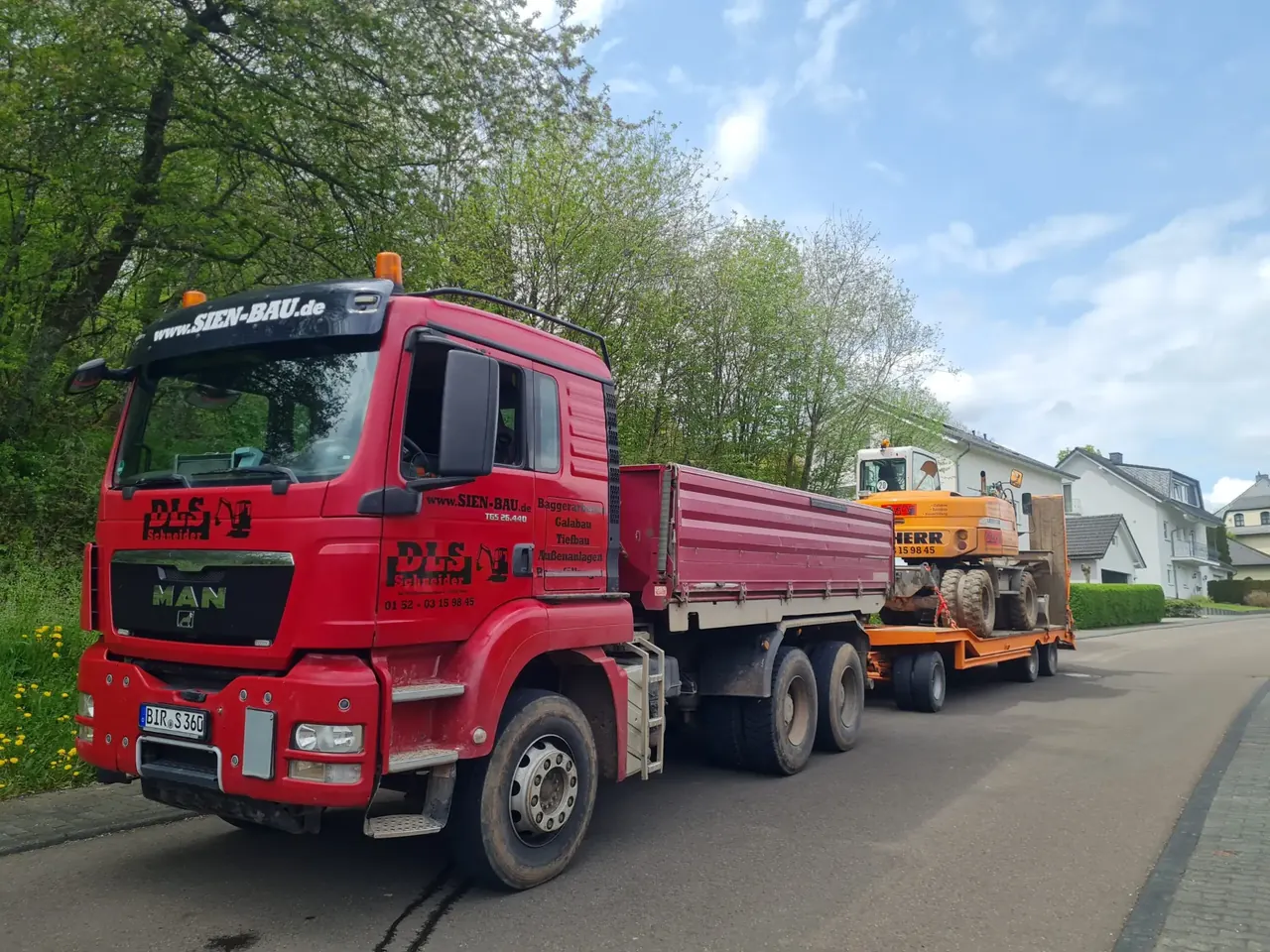 Beschrifteter DLS Schneider LKW mit Liebherr Bagger auf dem Tieflader